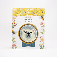 Punch needle kit packaging with floral design and bear illustration on a white background