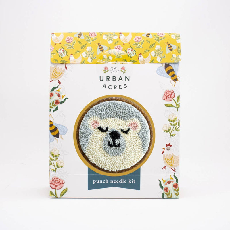 Punch needle kit packaging with floral design and bear illustration on a white background