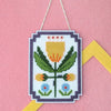 Framed tulip cross stitch on a pink felt background with a yellow felt frame