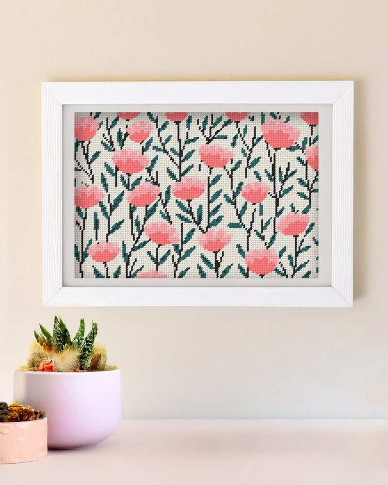 Framed needlepoint artwork with a floral design on a tan wall