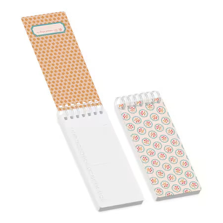 Thin notebooks, one with the first page folded open. The print is red and orange. 