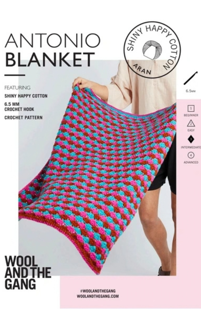 Model holding a pink, blue, and red crocheted blanket on a white and pink background with Wool & the Gang branding and text.