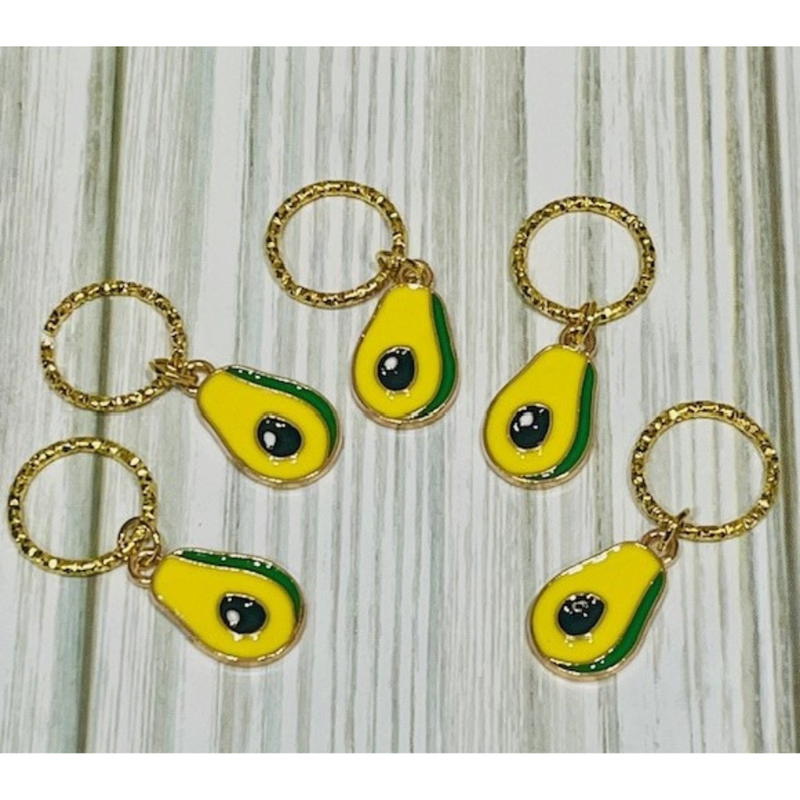 Avocado-shaped charms with gold loops on a wooden surface