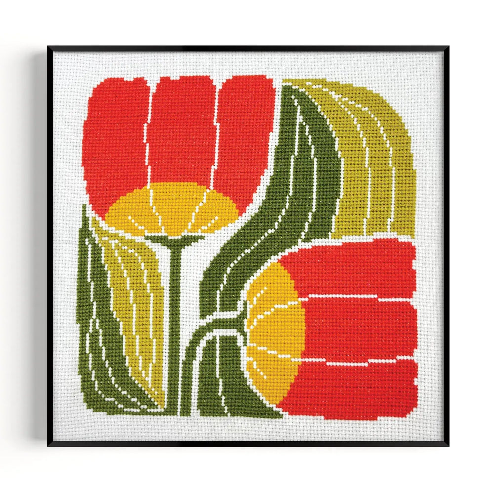 Framed cross-stitched artwork of red and yellow flowers with green leaves on a white background