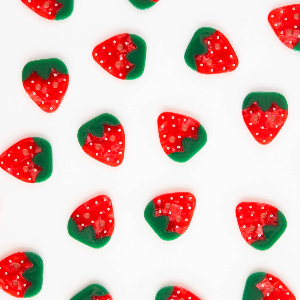Pattern of red strawberry-shaped buttons with green leaves on a white background