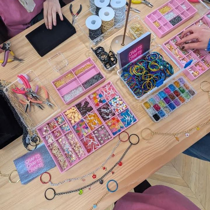 Table with jewelry-making supplies and tools on a wooden surface.