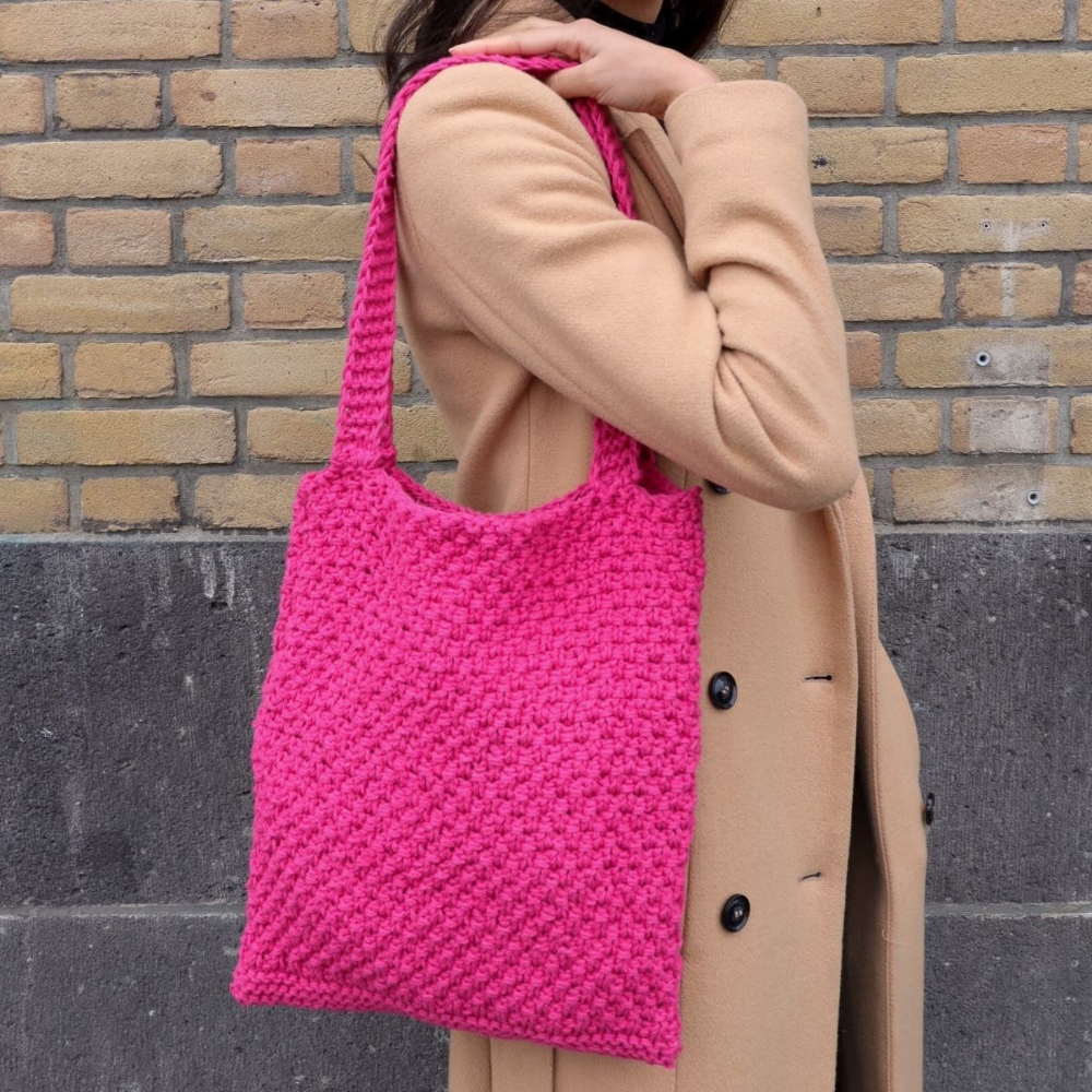 Woman holding hot pink knit tote bag
