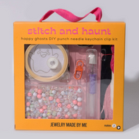 A DIY punch needle keychain kit in an orange gift box with a pink handle. The kit includes a spool of light tan thread, a ghost design template, a pink punch needle clip, a clear pen, and a tray of assorted pastel beads.