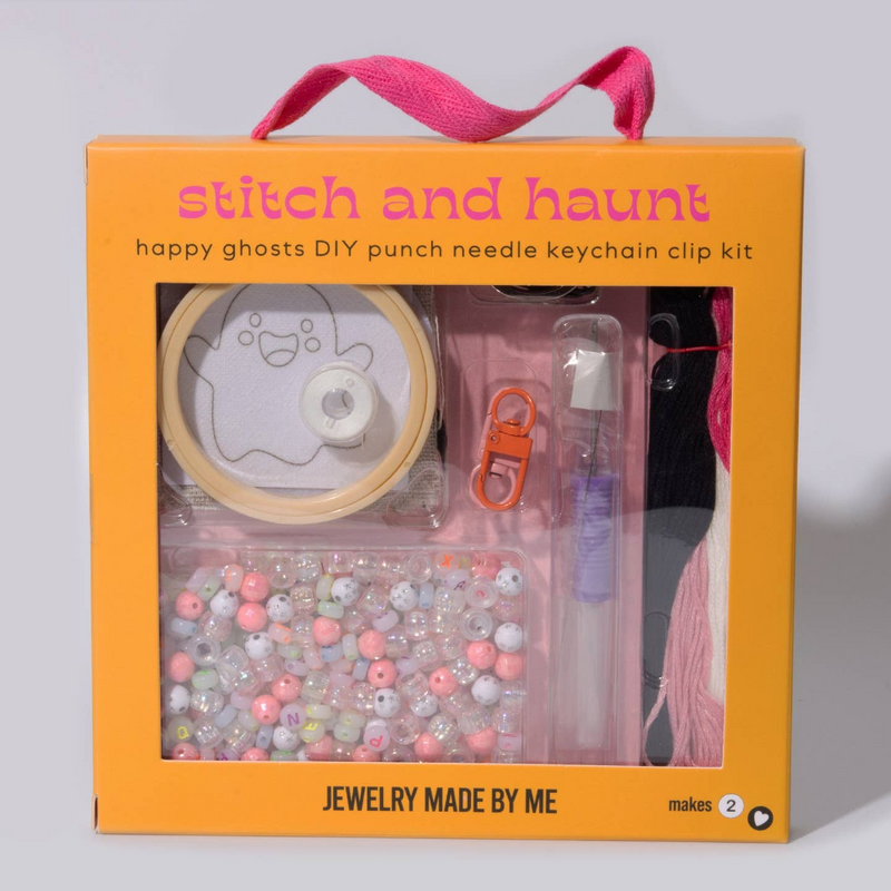 A DIY punch needle keychain kit in an orange gift box with a pink handle. The kit includes a spool of light tan thread, a ghost design template, a pink punch needle clip, a clear pen, and a tray of assorted pastel beads.