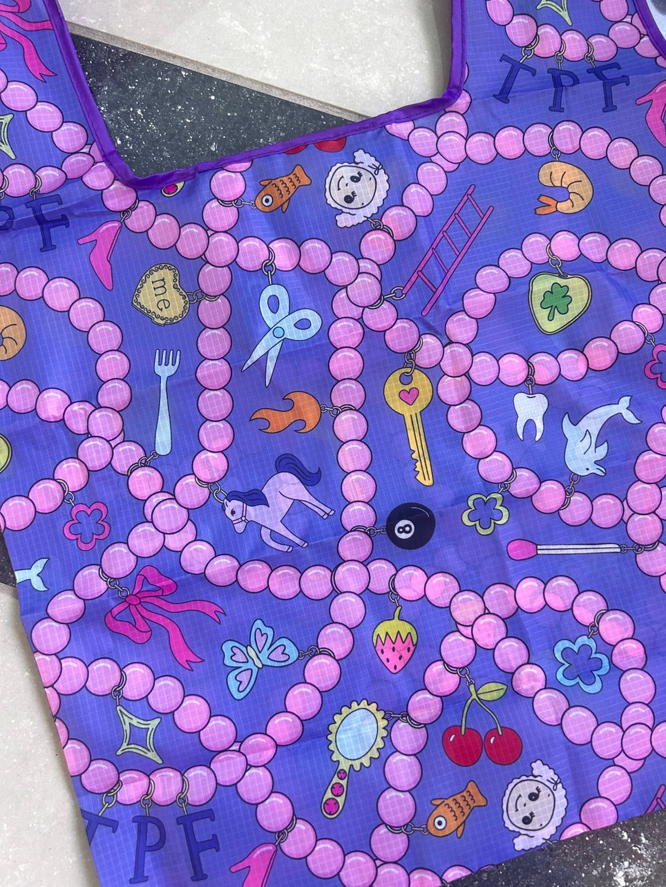 Purple fabric with pink beads and various colorful designs on a white background