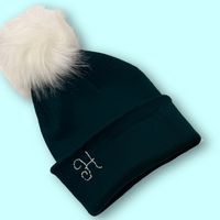 Black beanie with white pom-pom on a light blue background
