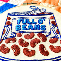Embroidery hoop with 'Full O' Beans' design featuring red beans and blue text.