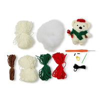 Crochet kit with yarn balls, a teddy bear figure, and crochet tools on a white background