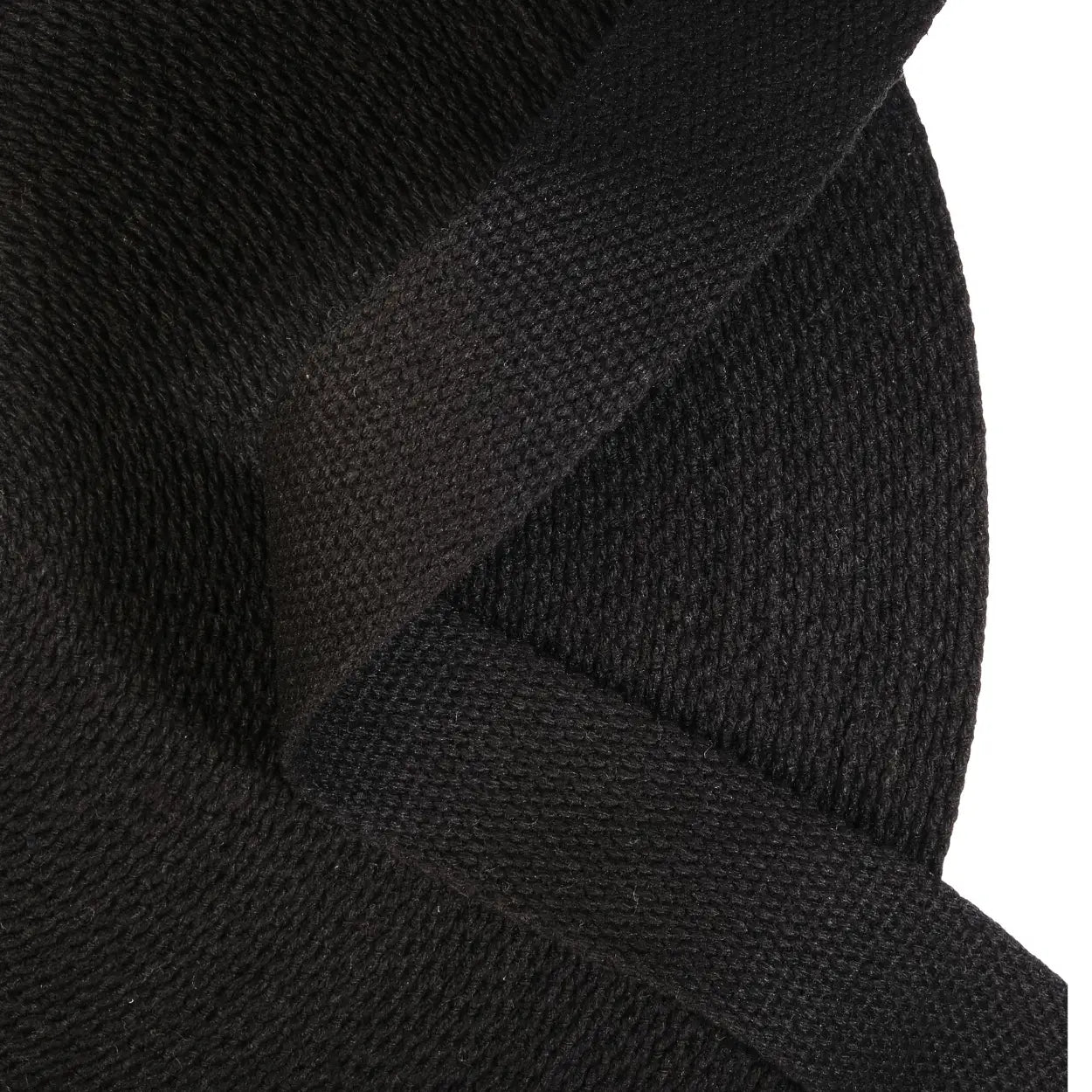 Close-up of a roll of black webbing with a white background