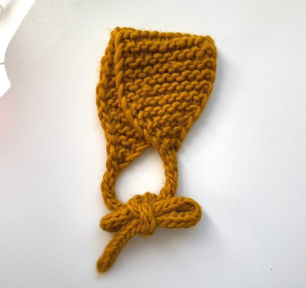 Knitted mustard yellow bonnet on a white background