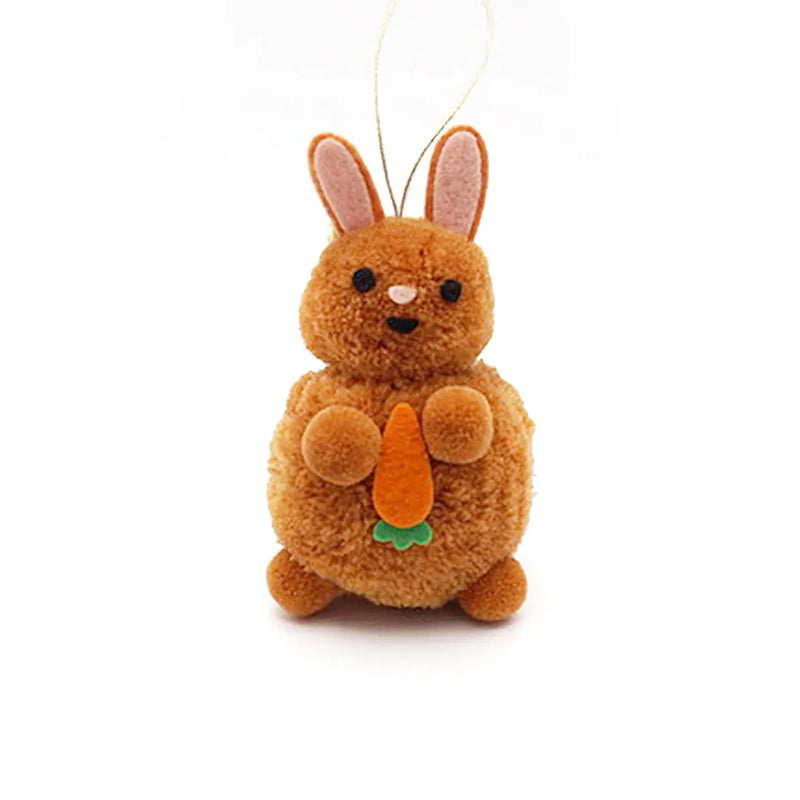 Bunny holding a carrot pom pom ornament on a white background.