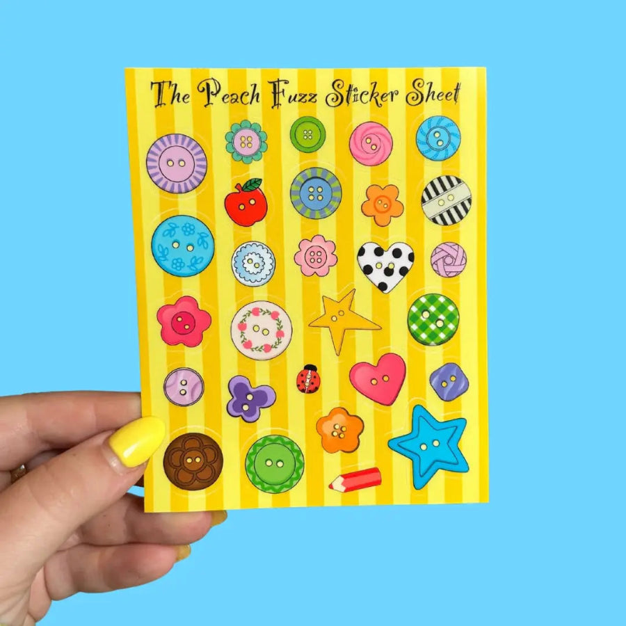 Hand holding a sticker sheet with colorful stickers on a blue background