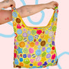 Colorful patterned bag held by a person against a pink background