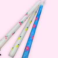 Three candles with floral designs on a light pink background