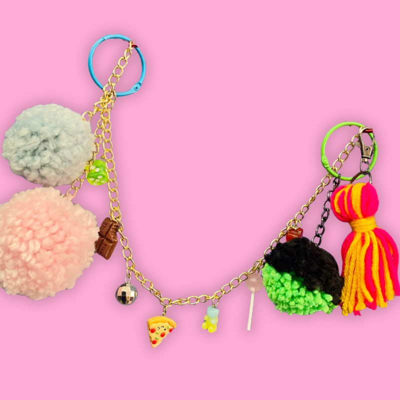 Colorful keychains with pom-poms and charms on a pink background