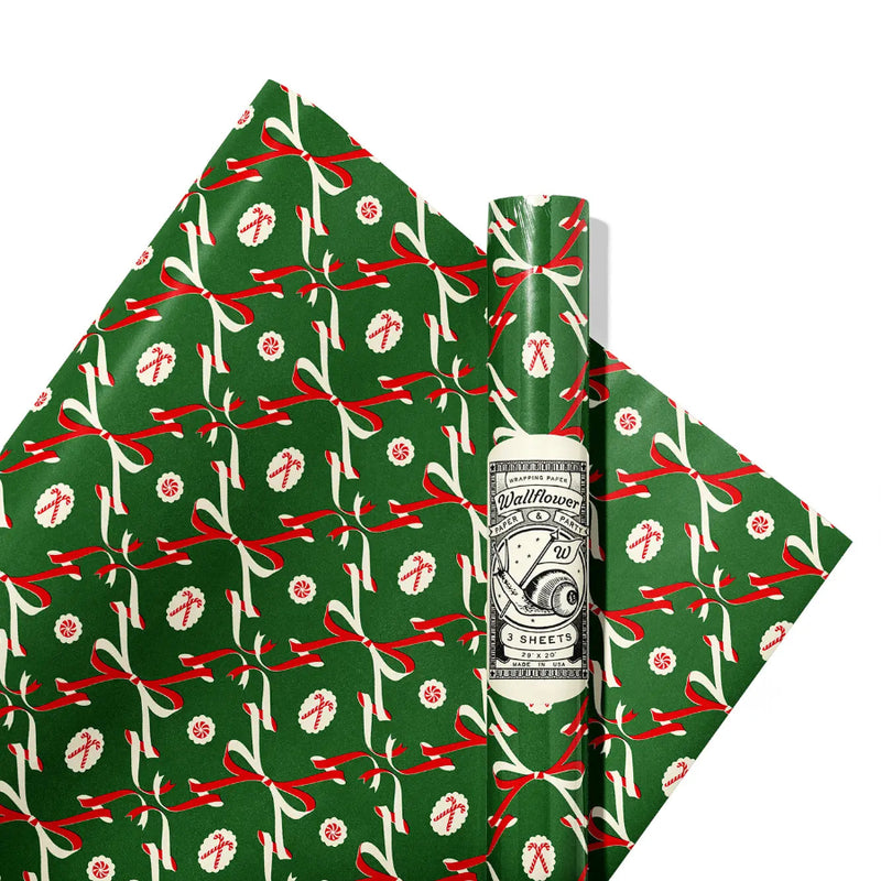 Green gift wrap with red and white ribbons and candy canes on a white background