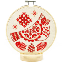 Red embroidered cardinal with folk elements on natural canvas in a white background