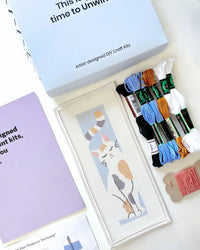 Needlepoint kit materials including a canvas and thread on a white background
