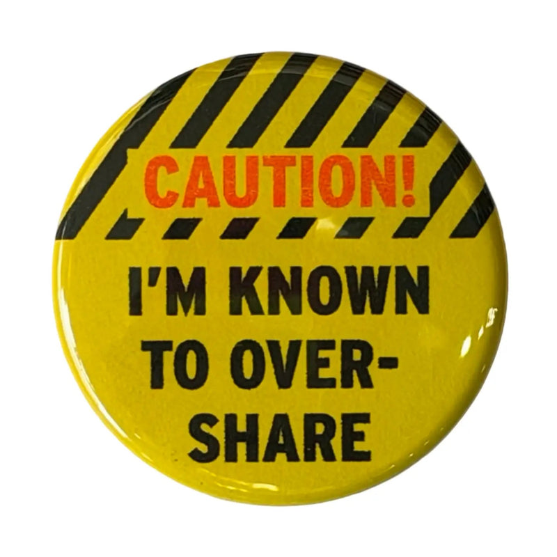 A yellow pin with a caution tape design on top and text that reads "Caution! I'm Known to Overshare". The word "Caution" is in red. 