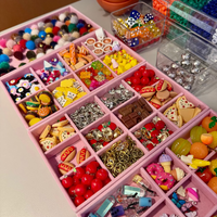 Assorted jewelry charms in a pink organizer on a table.