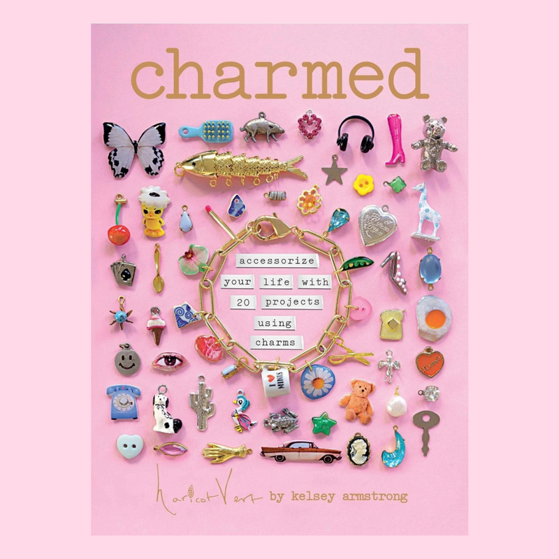 The book "Charmed" by Kelsey Armstrong with a cover featuring many cute charms against a pink background