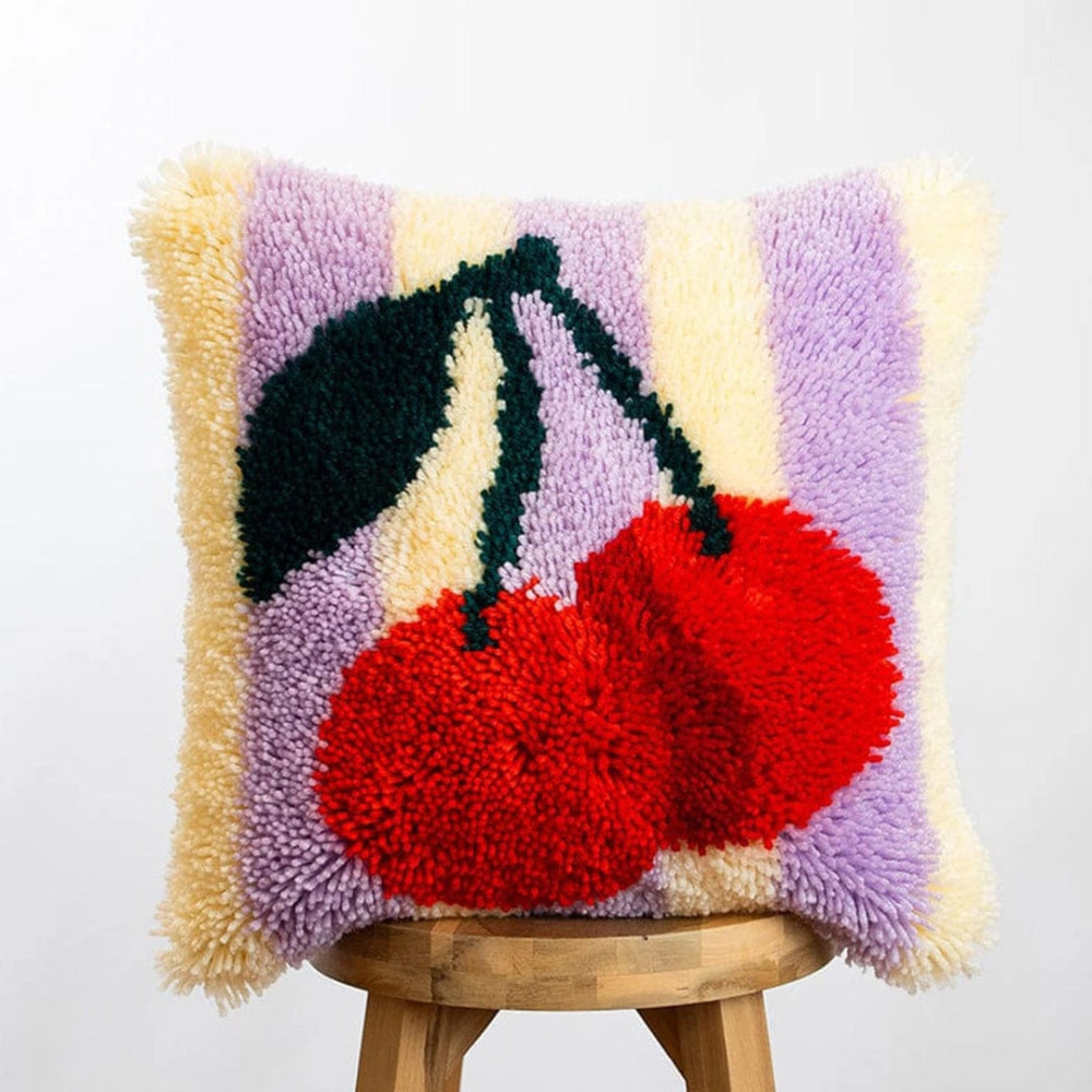 A fluffy pillow cushion featuring a red cherry pair with stem on a white and light purple striped background.