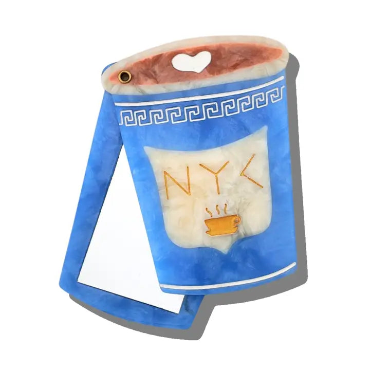 Blue and white compact mirror in the shape of a coffee cup with text reading "NYC" in gold.