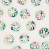 A close-up of multiple round faceted buttons arranged in a repeating pattern on a white background. Each button has a clear base with multicolored marbled inclusions in pastel and bright tones of green, blue, pink, yellow, and purple.