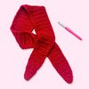 Red crocheted scarf with a pink crochet hook on a white background