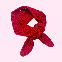 Red knitted headband with a bow on a pink background