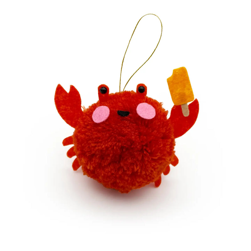Red crab holding a popsicle pom pom ornament on a white background.