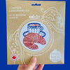 Embroidery kit packaging with a hand holding it against a blue background