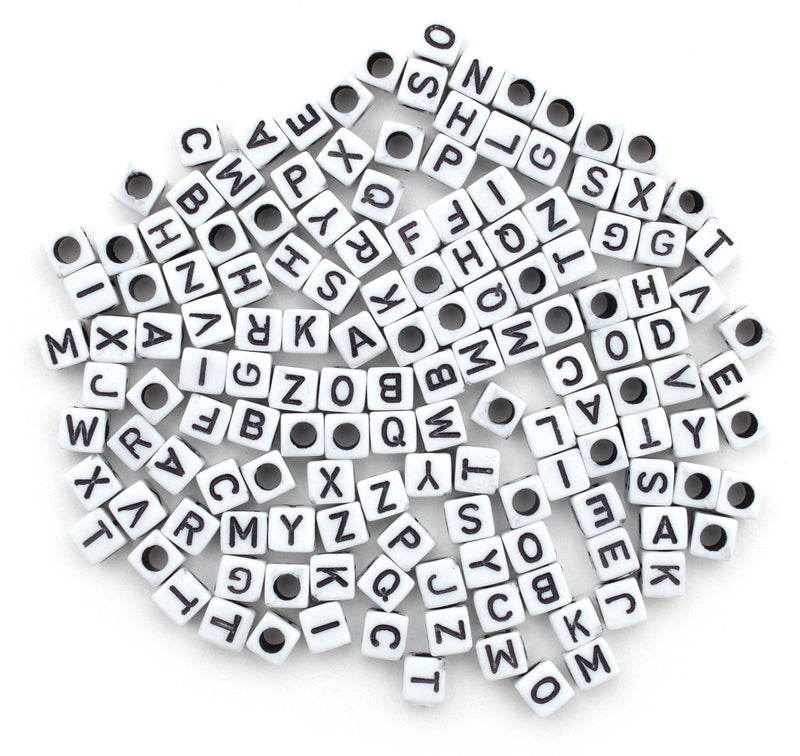 White alphabet beads with black letters scattered on a white background