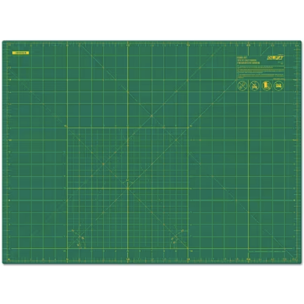 A green self-healing cutting mat with yellow grid lines and measurement markings, shown flat against a white background.