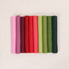 Various shades of felt sheet rolls in pinks, reds, and greens on a textured white background