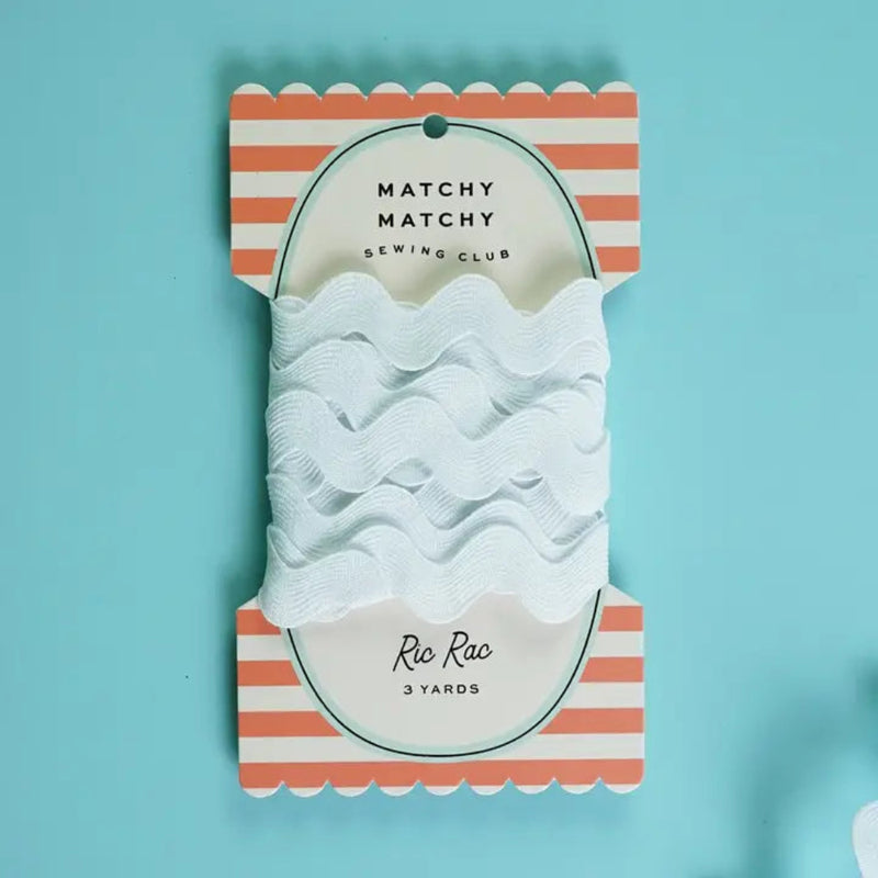 Packaged white ric rac trim with striped packaging on a light blue background