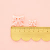 Small gold ruler with decorative bows on a pink background