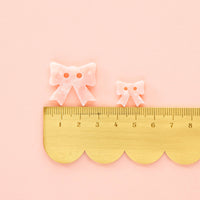 Small gold ruler with decorative bows on a pink background