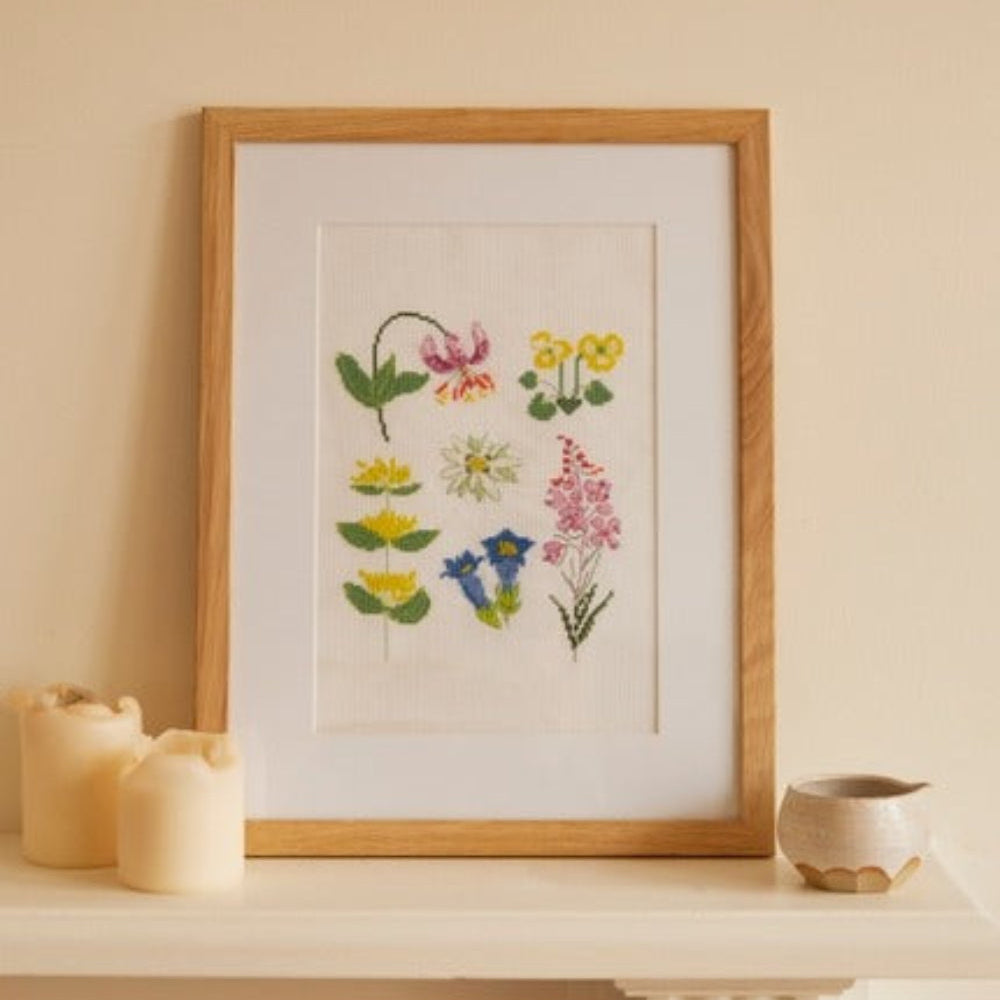 Framed botanical illustration on a table with candles and a bowl.