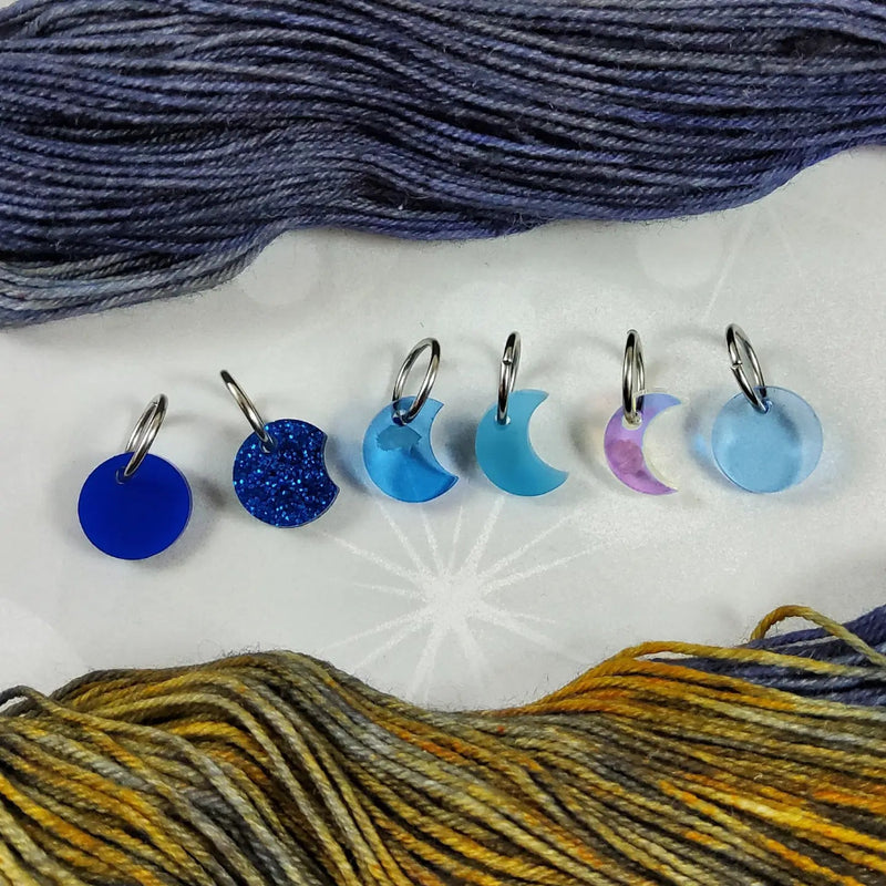 Set of colorful yarn markers with blue and golden yellow yarn in the background