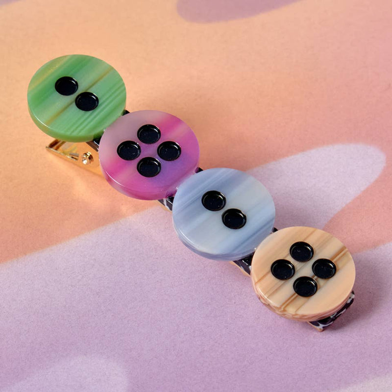 Set of four colorful button hair clips on a pastel background