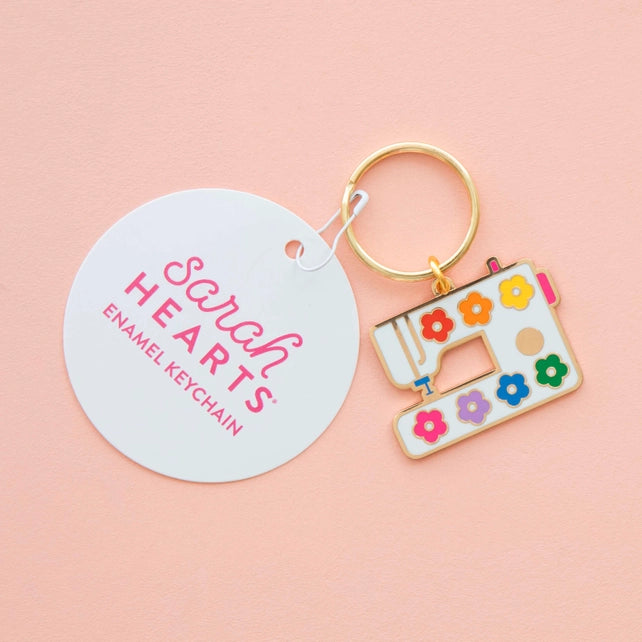 Colorful sewing machine keychain with 'Sarah Hearts' tag on a pink background