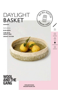 White and green crocheted basket with three lemons on a white and pink background with Wool and the Gang branding and text.