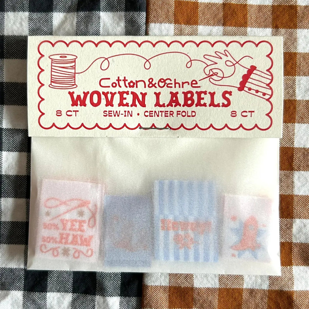 Pack of woven labels with visible text on a checkered fabric background