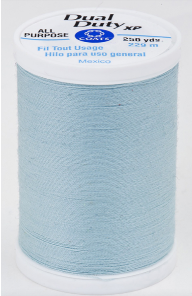 A spool of soft blue Dual Duty XP sewing thread with a white label featuring blue and black text, set against a plain white background.